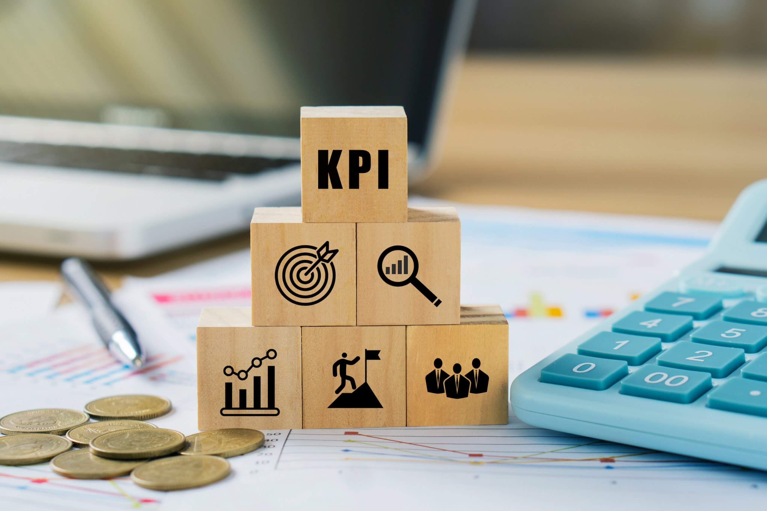 KPI, Key Performance Indicator.KPI icon on wooded cube with paperwork calculator and coin on a board room table. business goals, performance results and indicators.