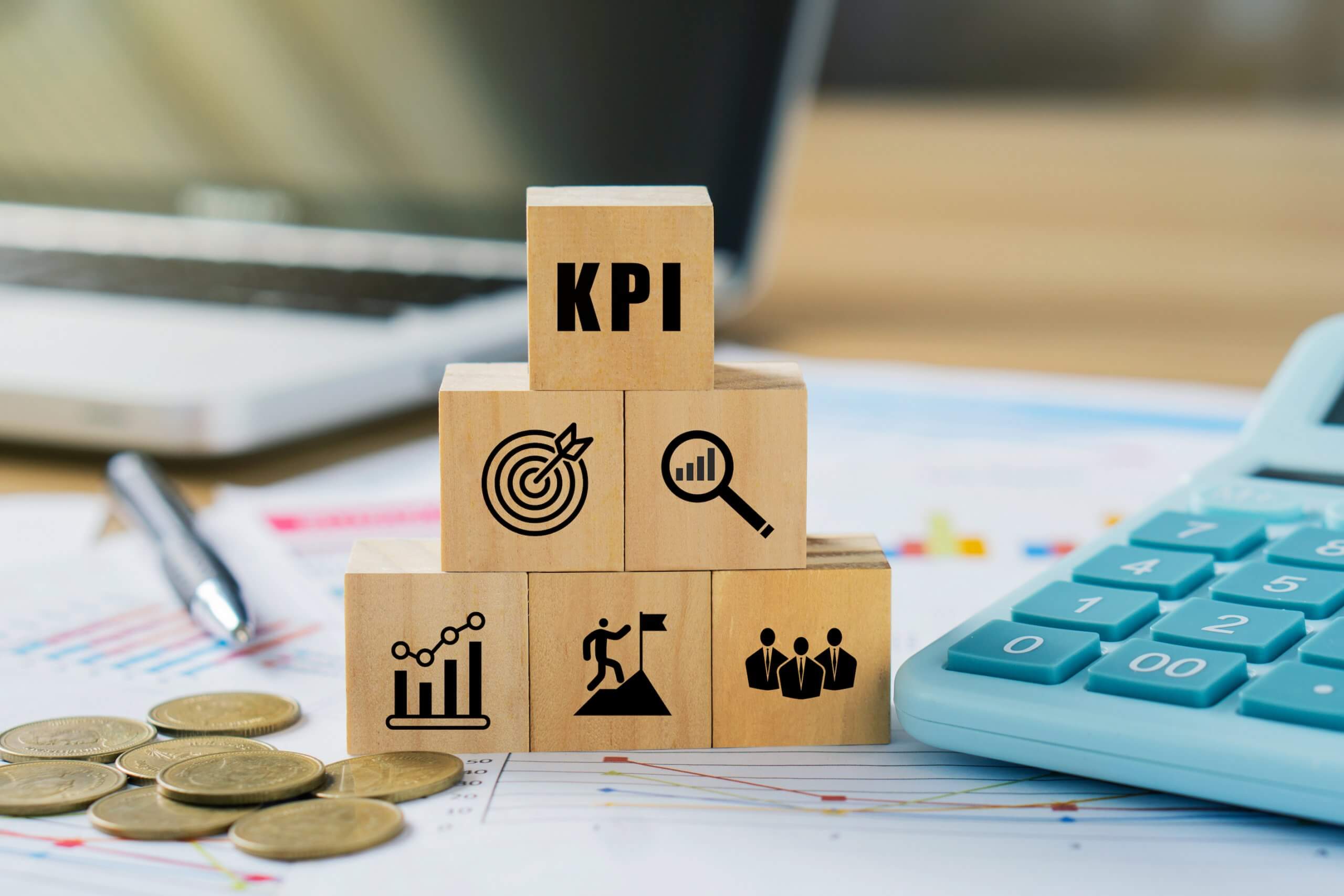 KPI, Key Performance Indicator.KPI icon on wooded cube with paperwork calculator and coin on a board room table. business goals, performance results and indicators. KPI, Key Performance Indicator.KPI icon on wooded cube with paperwork calculator and coin on a board room table. business goals, performance results and indicators.